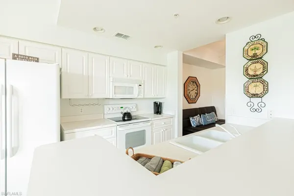 a large white kitchen with a lot of cabinets and a wooden floor