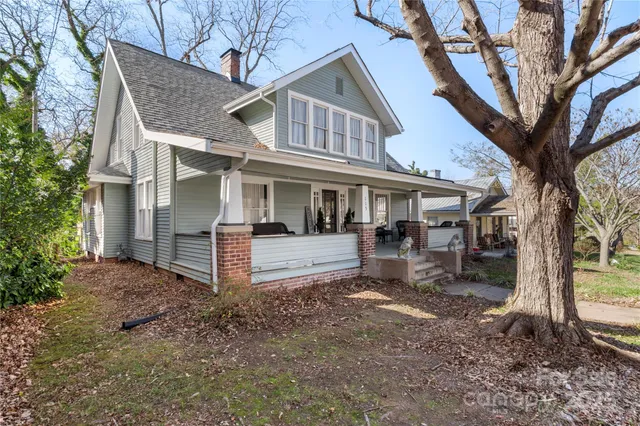 a view of a white house with large trees and a large tree