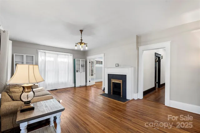 a view of an empty room with wooden floor fireplace and a window