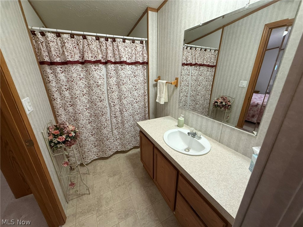 2933 Rabbit Drive Dennison, OH 44621 - Photo 20 of 28 Bathroom featuring vanity, wallpapered walls, a textured ceiling, and a shower with curtain