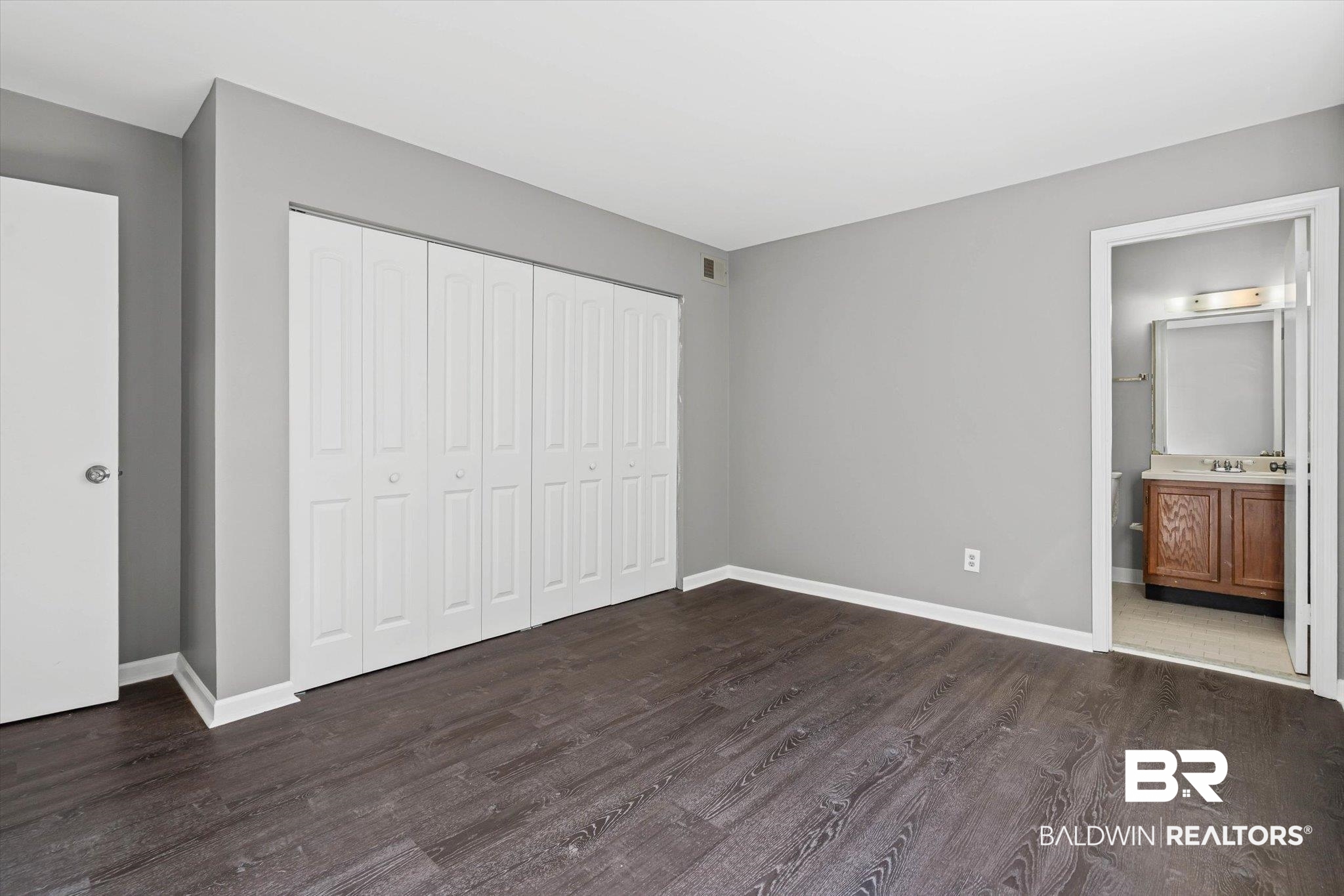 6701 Dickens Ferry Road, Unit 100 Mobile, AL 36608 - Photo 11 of 24 Unfurnished bedroom featuring dark wood finished floors, a closet, and connected bathroom
