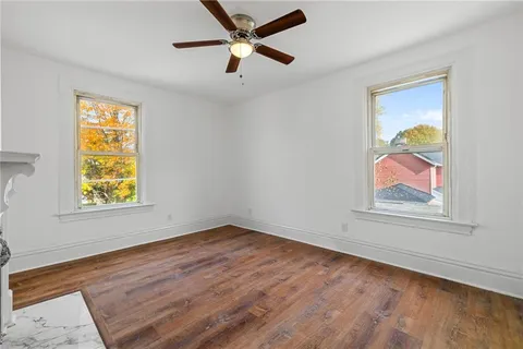 a view of an empty room with window and wooden floor