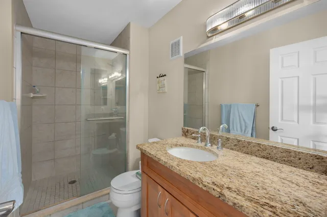 a bathroom with a granite countertop sink a toilet and shower