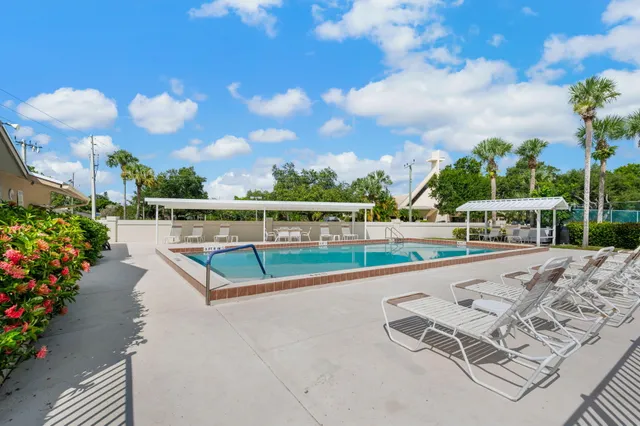 a view of swimming pool with seating space and trees in the background