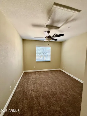 an empty room with a ceiling fan and window