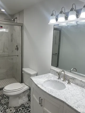 a bathroom with a granite countertop sink a toilet and shower