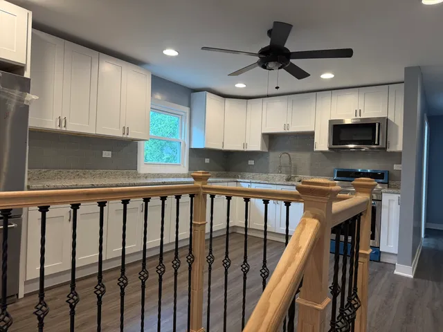 a kitchen with kitchen island granite countertop a stove sink microwave and cabinets