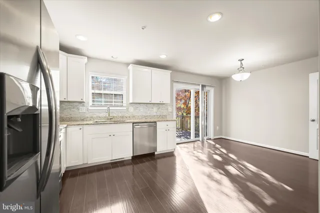 a open kitchen with granite countertop a stove top oven a sink dishwasher a refrigerator and white cabinets with wooden floor