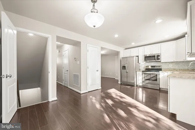 a kitchen with stainless steel appliances a refrigerator and wooden floor