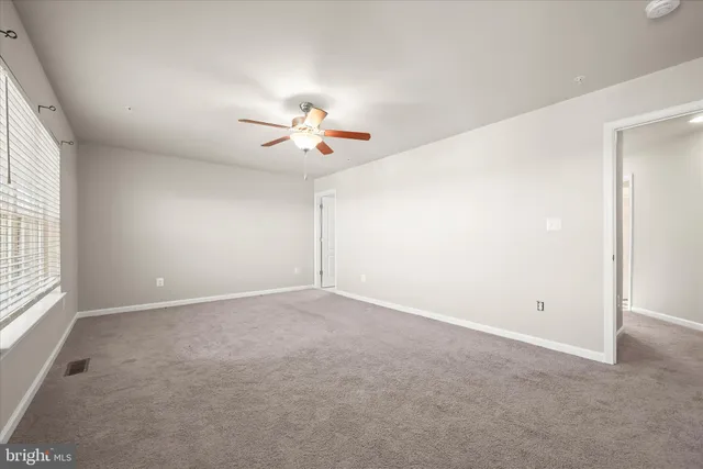 an empty room with a window and a ceiling fan