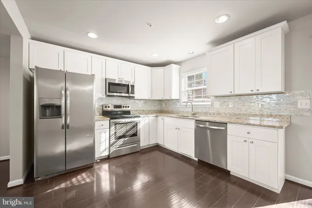 a kitchen with stainless steel appliances granite countertop a refrigerator a sink a stove a microwave and white cabinets