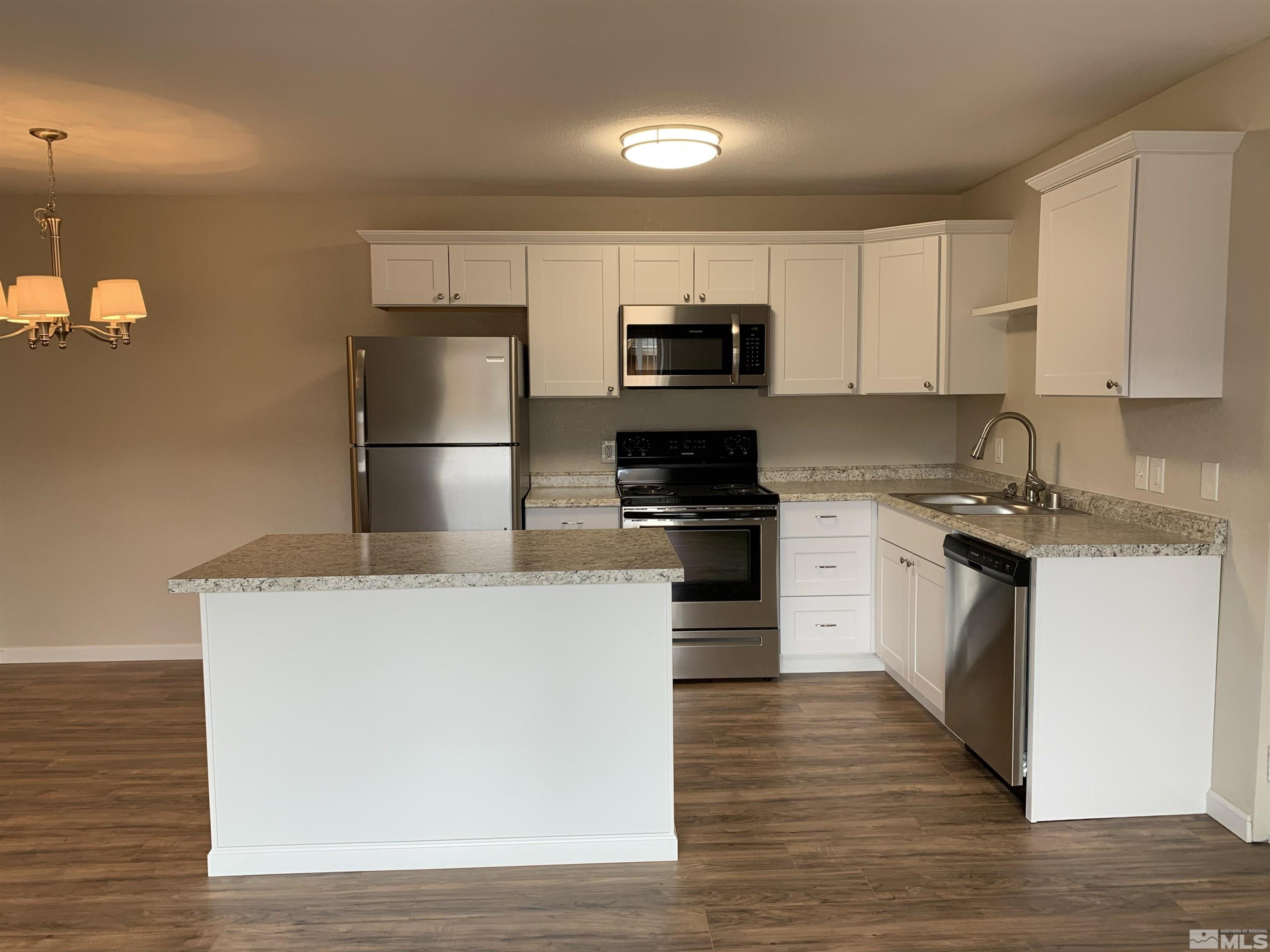 2150 Sutro Street, Unit A3 Reno, NV 89512 - Photo 3 of 8 a kitchen with kitchen island a white counter top space cabinets and stainless steel appliances