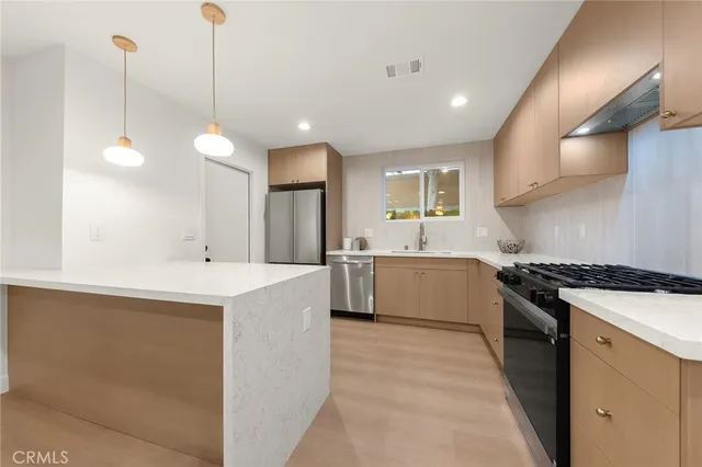 a large kitchen with stainless steel appliances granite countertop a sink a stove and a refrigerator