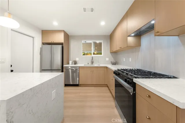 a large kitchen with stainless steel appliances granite countertop a stove a sink and a refrigerator