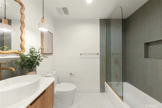 a bathroom with a sink a toilet a mirror and shower