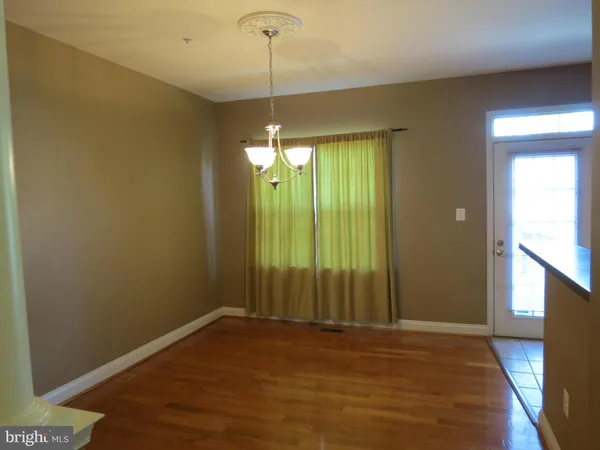 a view of an empty room with window and hardwood floor