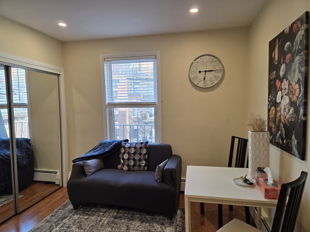 a living room with furniture a clock on wall and a window