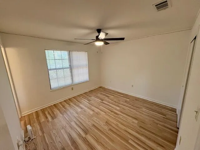 an empty room with windows and fan
