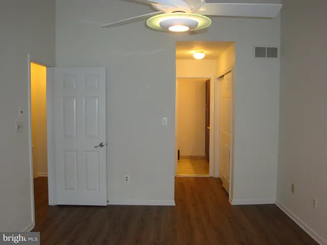an empty room with wooden floor fan and windows