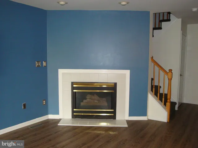 a living room with wooden floor and a fireplace