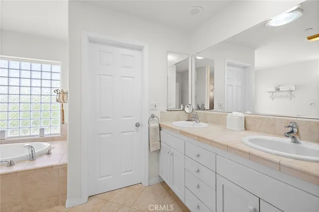 a bathroom with a granite countertop tub sink and mirror