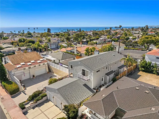 an aerial view of a city with lots of residential buildings and ocean view in back