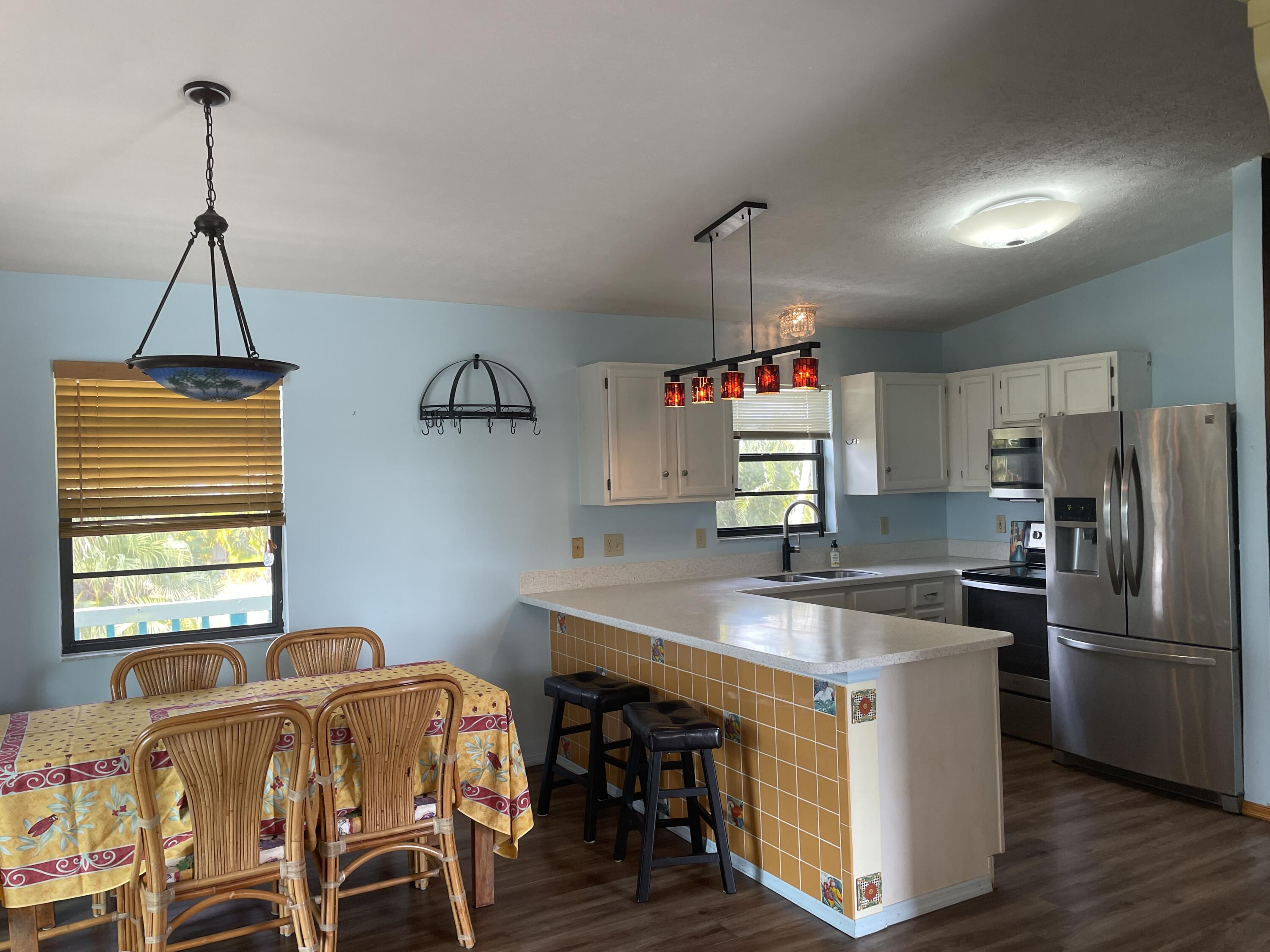 744 Blackbeard Road Summerland Key, FL 33042 - Photo 8 of 39 a kitchen with stainless steel appliances granite countertop a sink dishwasher a stove and a refrigerator with wooden floor