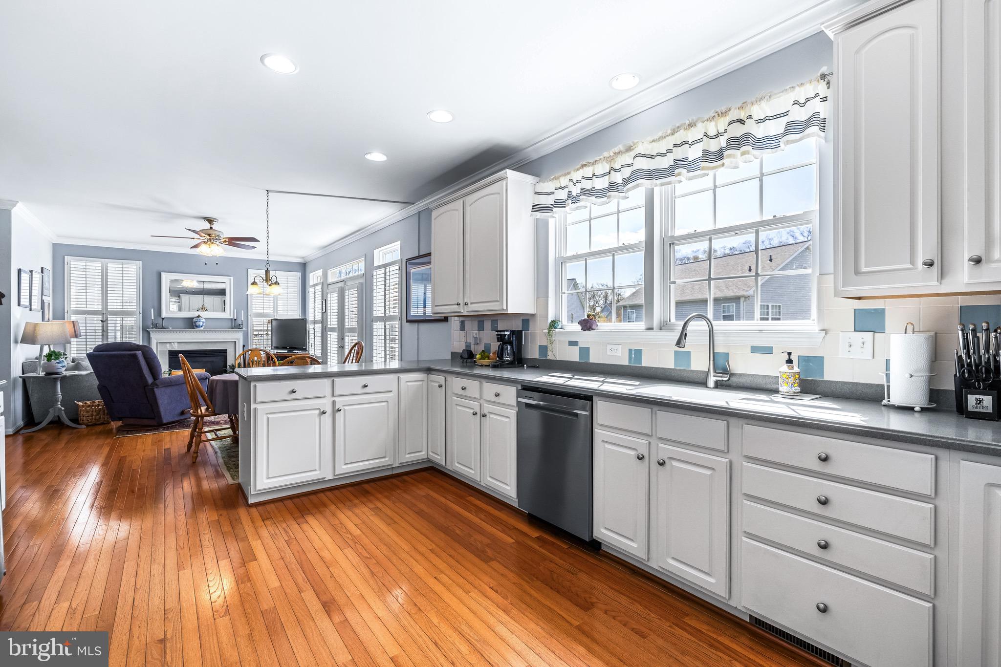 1713 Mystic Circle Baltimore, MD 21221 - Photo 13 of 37 a large white kitchen with cabinets a sink dishwasher a dining table and chairs with wooden floor