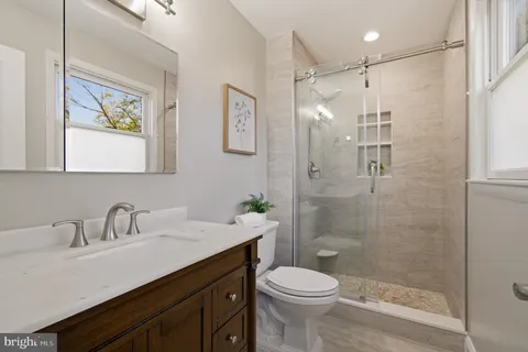 a bathroom with a shower sink vanity mirror and toilet