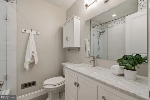 a bathroom with a granite countertop sink a toilet and a mirror