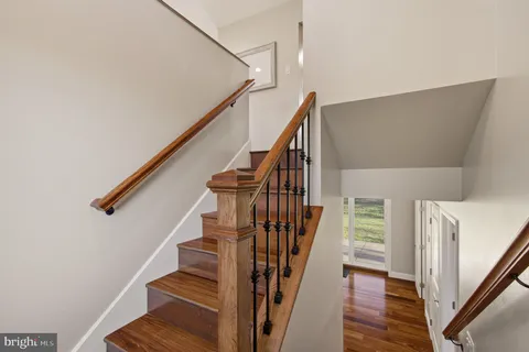 a view of staircase with wooden floor and white walls