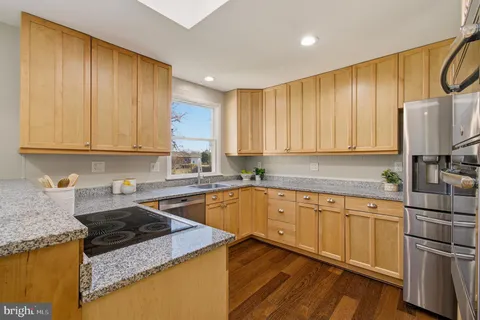 a kitchen with granite countertop wooden cabinets stainless steel appliances and a sink