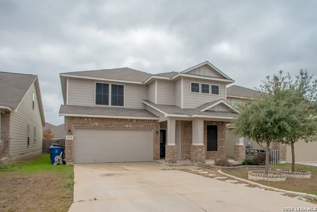 a front view of a house with a garden and tree