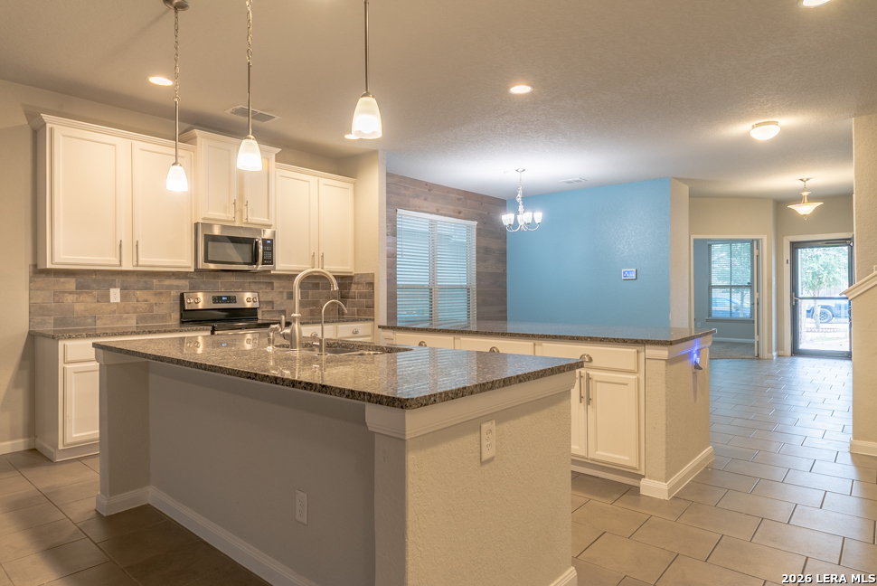 10230 Midsummer Meadow Converse, TX 78109 - Photo 11 of 37 a kitchen with stainless steel appliances granite countertop a sink a stove a microwave a counter space and cabinets