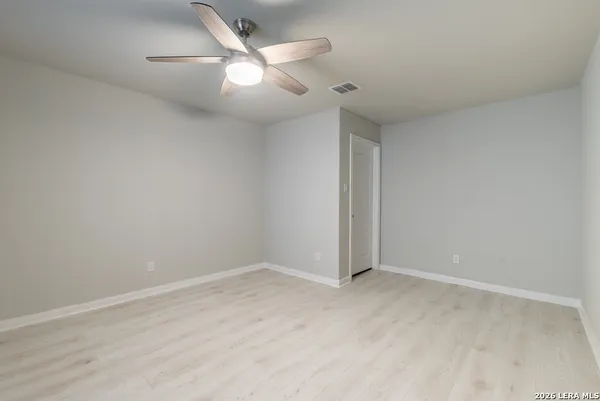 an empty room with a ceiling fan and wooden floor