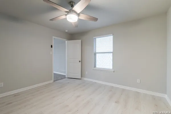 an empty room with wooden floor ceiling fan and windows