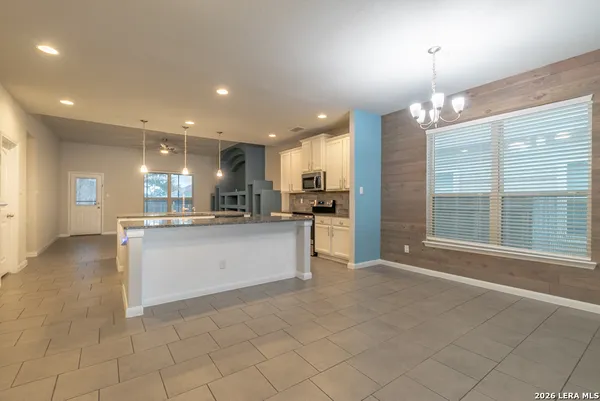 a view of kitchen with kitchen island granite countertop a stove a sink a refrigerator and white cabinets with wooden floor