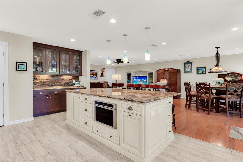 319 East Spring Valley Road Richardson, TX 75081 - Photo 2 of 22 Kitchen island with integrated microwave, pendant lighting, and light-toned tile flooring