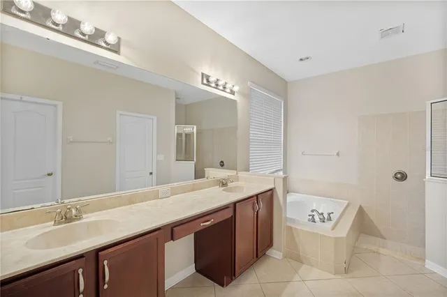a bathroom with a sink double vanity granite tub shower and a mirror