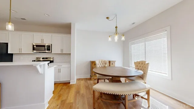 a kitchen with stainless steel appliances kitchen island granite countertop a sink a stove a dining table and chairs