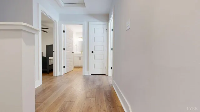 a view of a hallway with wooden floor and a bathroom