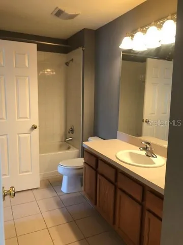 a bathroom with a granite countertop sink toilet mirror and bathtub