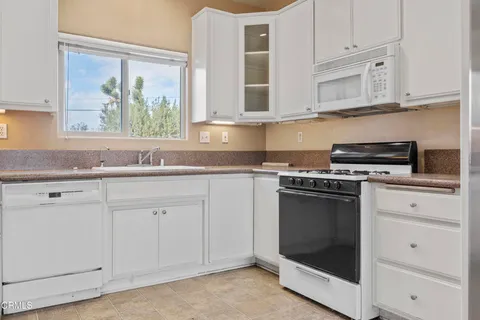 a kitchen with granite countertop white cabinets and appliances