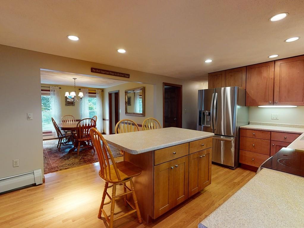 17 Nyra Road Stow, MA 01775 - Photo 7 of 26 a kitchen with stainless steel appliances granite countertop a refrigerator a sink dishwasher a dining table and chairs with wooden floor