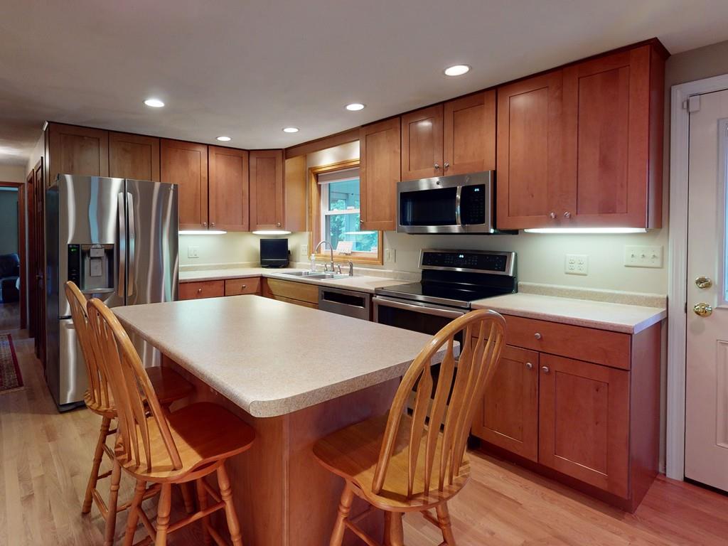 17 Nyra Road Stow, MA 01775 - Photo 8 of 26 a kitchen with stainless steel appliances granite countertop a stove a refrigerator a microwave a sink and a island with wooden floor