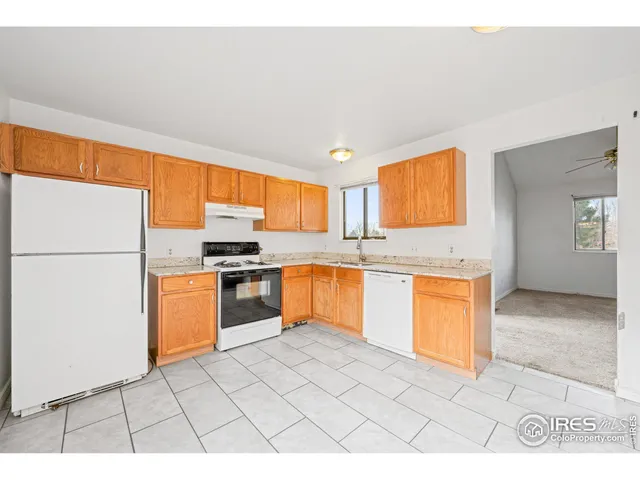 a open kitchen with granite countertop a sink dishwasher a stove a refrigerator with white cabinets and wooden floor