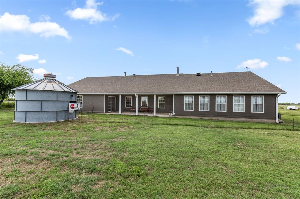 13315 Highway 281 Scotland, TX 76379 - Photo 32 of 40 Rear exterior featuring covered patio with pillars, shingled roof, multiple windows with white trim and a grain bin
