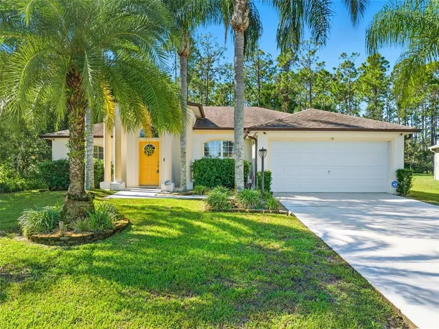a front view of a house with a yard and palm trees