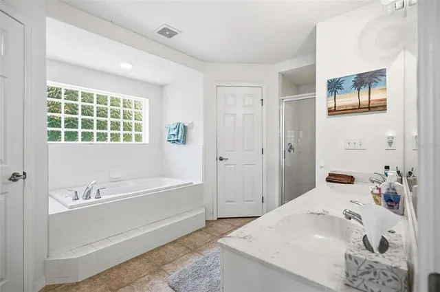 a spacious bathroom with a granite countertop tub sink a mirror a shower and vanity