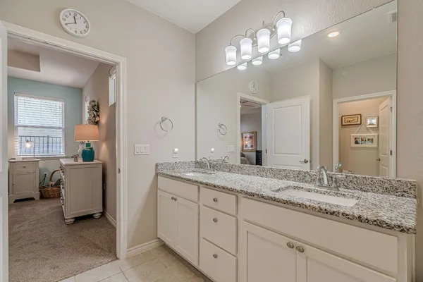 a bathroom with a granite countertop double vanity sink a window and a mirror